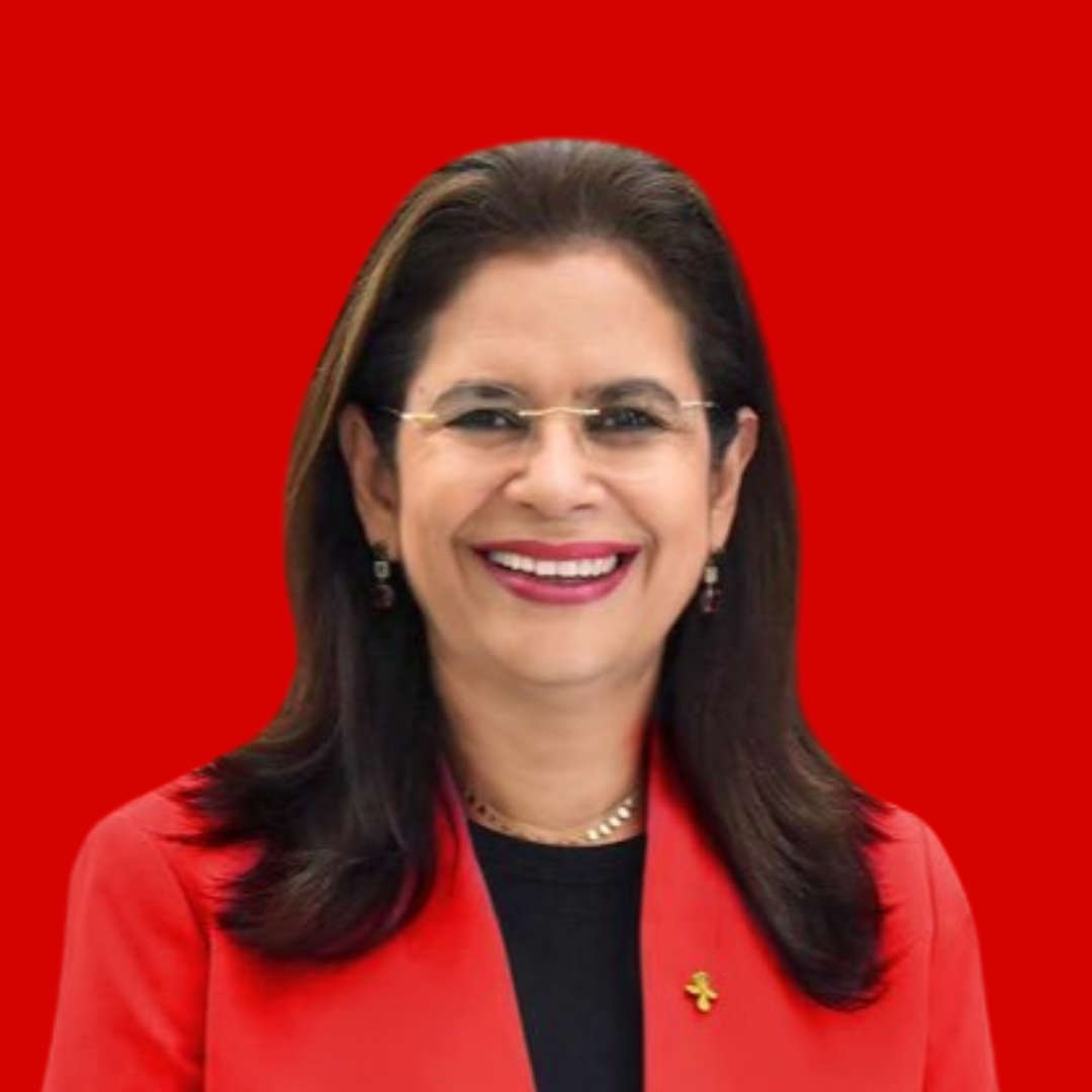 Una mujer de pelo largo y oscuro, con gafas, americana roja y top negro, sonríe sobre un fondo rojo brillante.