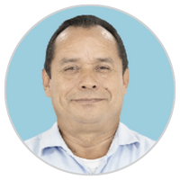 Retrato de un hombre de mediana edad con el pelo corto y oscuro, vestido con una camisa de cuello azul claro, sonriendo ligeramente, retratado sobre un fondo circular azul claro.
