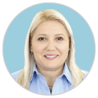 Retrato de una mujer con el pelo liso, rubio claro, vestida con una camisa de cuello azul claro y sonriendo, sobre un fondo azul claro.