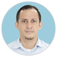 Retrato de un hombre de pelo corto y oscuro, piel clara y perilla recortada, con camisa de cuello azul claro, sobre un fondo circular azul claro.