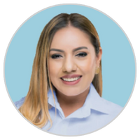 Una mujer con el pelo largo, liso y rubio y una camisa de cuello azul claro sonríe delante de un fondo azul claro sólido.